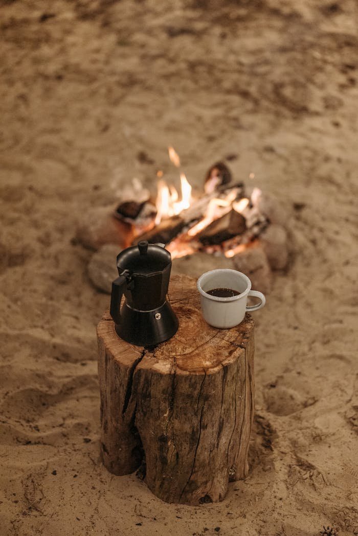 Mastering the First Impression: Your intriguing post title goes here A serene campfire setting with coffee and moka pot on a wooden log, perfect for outdoor lovers.